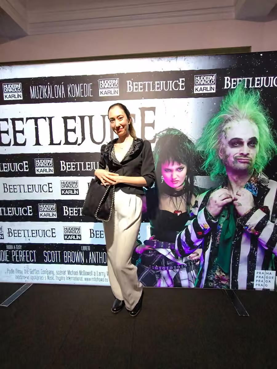 Oya Canli standing beside a Beetlejuice promotional backdrop at Hudební divadlo Karlín.