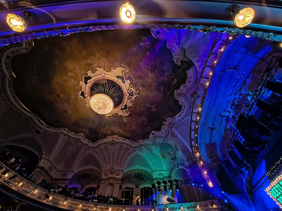 The ornate ceiling and chandelier of Hudební divadlo Karlín lit for Beetlejuice.
