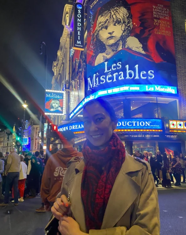 Oya Canli vor dem Sondheim Theatre im Londoner West End mit einem Plakat für das Musical Les Misérables im Hintergrund.
